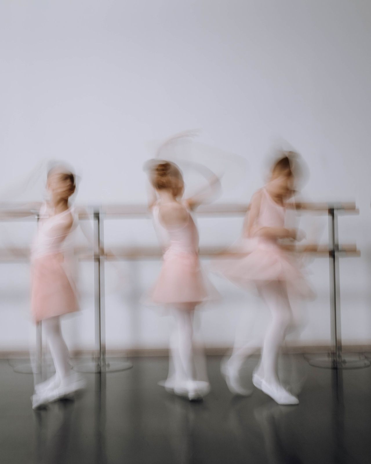 Young dancers in pink at the barre, blurred in motion